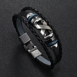 Detailed macro view of black braided leather bracelet with blue beads and X-shaped alloy charm