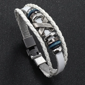 Detail view of white braided leather bracelet with vintage metal X-shape and blue wooden beads