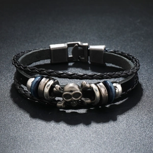 Macro shot of multi-layer leather bracelet featuring vintage silver skull and crossbones charm