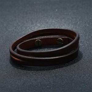 Close-up detail of dark brown layered leather bracelet with bronze screw hardware