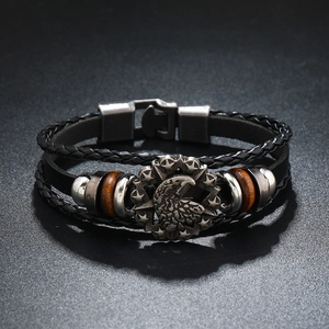 Close-up of leather punk bracelet with engraved eagle head metal badge and wooden beads