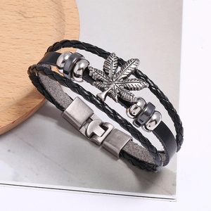 Close-up of multilayer punk leather bracelet with leaf pendant and retro metal buckle