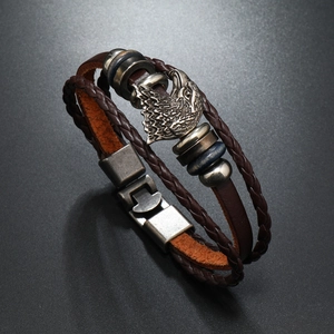 Macro detail of men's multilayer brown leather bracelet with silver eagle charm
