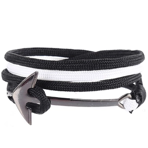 Close-up of nautical rope bracelet with a gun-black metal anchor hook on white background