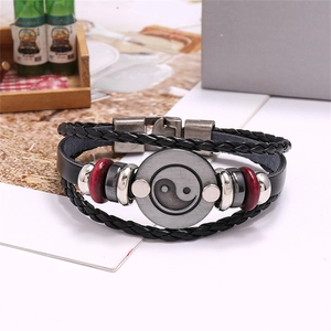 Macro view of vintage multilayer leather bracelet with Tai Chi Yin Yang charm and red beads