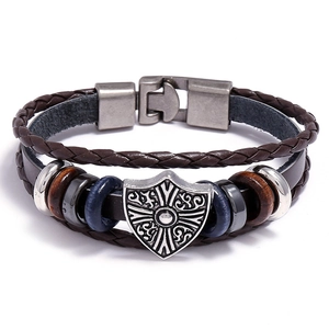 Detail of vintage leather bracelet with shield charm and wooden beads on white background