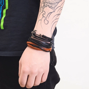 Detail view of multi-layer leather bracelet with bronze anchor clasp on male wrist