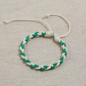 Detail of green and beige hand-woven rope bracelet with adjustable sliding knot closure