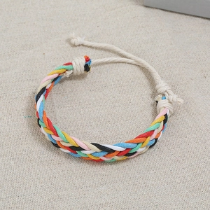 Detailed macro view of a colorful handmade braided rope bracelet on rustic linen surface