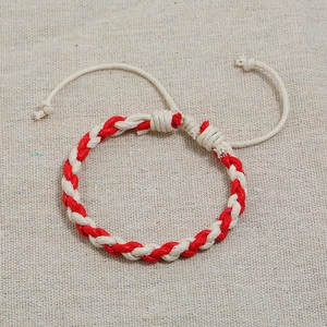Close-up of handmade red and beige braided cotton bracelet with adjustable slide knot