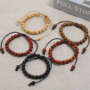 Adjustable wooden bead bracelets in five assorted colors displayed on linen background