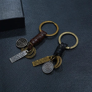 Macro detail of hand-woven vintage leather keychains with bronze charms and engraved tags