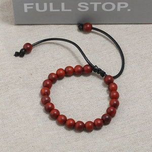 Detailed macro view of polished red wooden beads on adjustable black cord bracelet