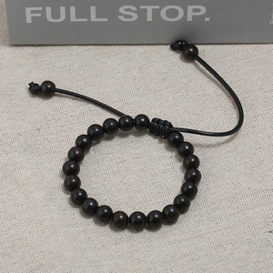 Close-up of minimalist wooden beaded bracelet with adjustable black woven cord closure