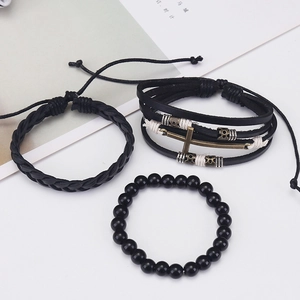Close-up of three-piece vintage black leather bracelet set with cross and anchor charms