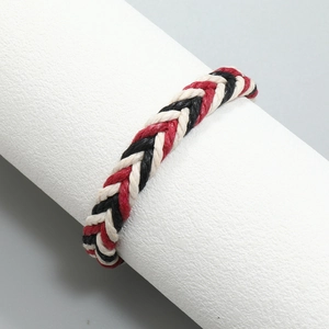 Detail van de driekleurige handgeweven koordarmband in de kleuren rood, zwart en beige crème