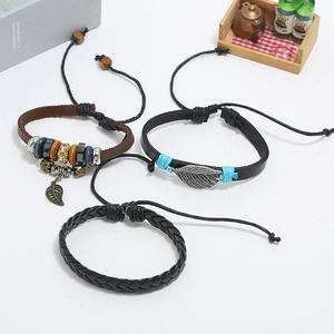 Detail of three-piece vintage leather bracelet set with feather charm and ethnic beads