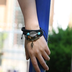 Detail of multi-layer braided leather bracelet with vintage metal leaf charm and beads