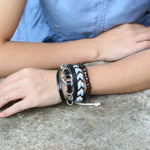 Detail view of multi-layer braided leather bracelets and wooden beads on a model wrist
