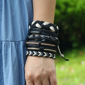 Close-up of stacked leather bracelets with woven layers on a model against nature background