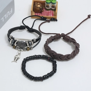 Close-up of three-piece multilayer leather bracelet set with metallic charms and beads