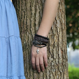 Detail of vintage multilayer braided leather bracelet with a silver fishbone charm on wrist