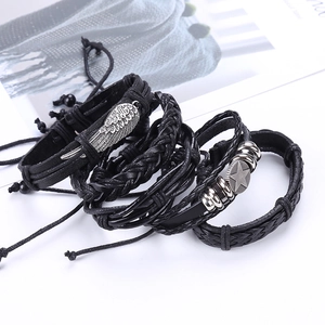 Retro multilayer black leather bracelet set with silver wing and star charms on white background