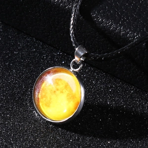Macro detail of moon celestial glass pendant on a black textured cord necklace