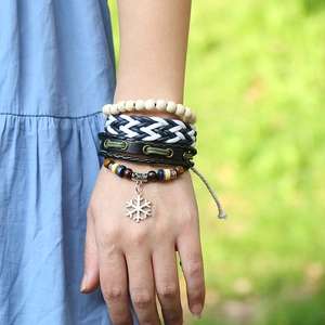 Detailed close-up of multilayered braided leather bracelets with silver snowflake pendant