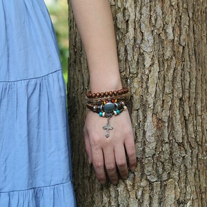 Detail of bohemian multilayer leather bracelet with wooden beads and a metal cross charm
