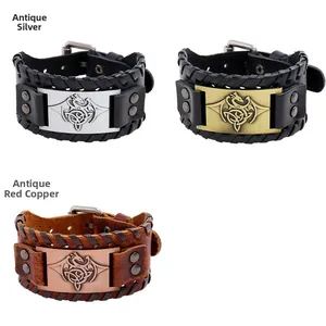 Detail of vintage woven leather bracelets featuring antique silver and copper dragon plaques