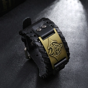 Detail of vintage braided leather bracelet featuring a bronze totem plaque and punk rivets
