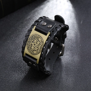 Detail of vintage black braided leather wristband with bronze tree of life metal emblem