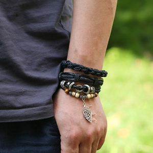 Close-up of layered black leather bracelets with metallic leaf pendant on a wrist