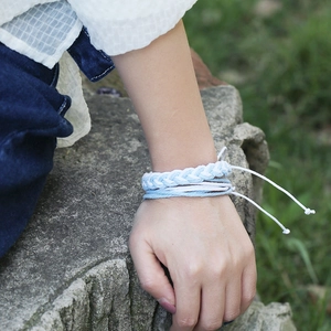 Détail d'un bracelet tressé à la main bleu et blanc avec nœud réglable sur fond de roche