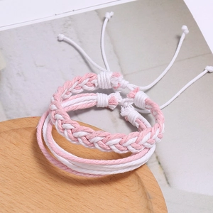 Détail de bracelets de couple tressés à la main rose et blanc avec nœuds coulissants