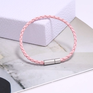 Détail du bracelet tressé en cuir rose avec fermoir magnétique en argent sur boîte cadeau