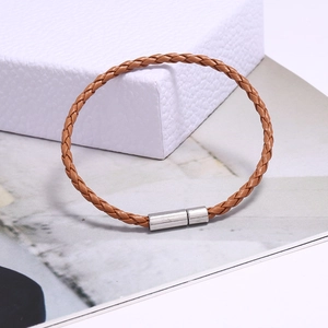 Gros plan du bracelet en cuir tressé marron avec fermoir en métal argenté sur magazine