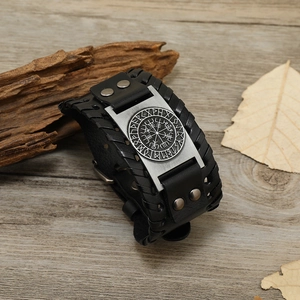 Detailopname van Viking kompas lederen armband met gevlochten randen op houten decor