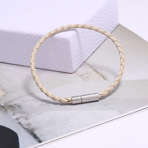 Détail d'un bracelet en cuir tressé beige avec un fermoir magnétique en métal argenté