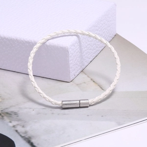 Détail d'un bracelet en cuir blanc tressé avec un fermoir magnétique en métal argenté