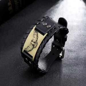 Dettaglio del bracciale vichingo in pelle nera intrecciata con stemma dell'aquila in ottone