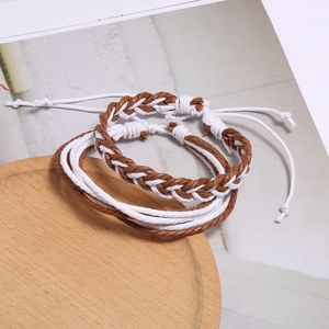 Détail de bracelets bohèmes tissés à la main avec nœuds réglables sur un plateau en bois