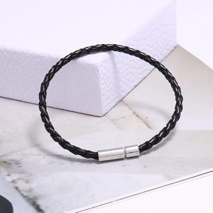 Détail d'un bracelet en cuir tressé noir avec fermoir cylindrique en métal argenté