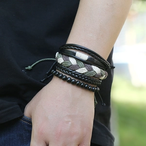Gros plan de bracelets multicouches en cuir tressé rétro et perles sur un poignet masculin