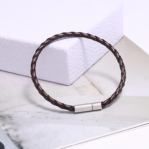 Détail d'un bracelet en cuir tressé marron foncé avec fermoir magnétique cylindrique