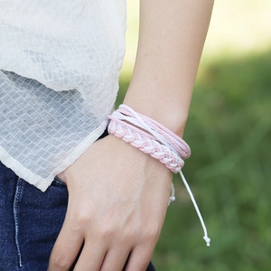 Détail de bracelets bohèmes faits main rose et blanc dans un cadre naturel extérieur