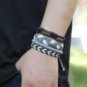 Gros plan d'un ensemble de quatre bracelets vintage en cuir tressé au poignet d'un homme