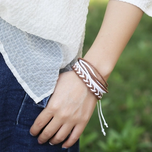 Détail d'un bracelet tressé multicouche avec cordons marron et blanc porté au poignet
