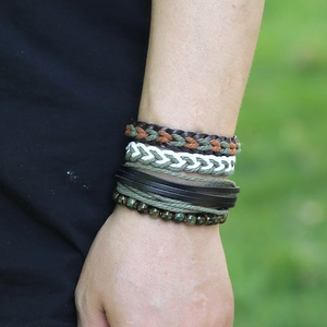 Gros plan de bracelets vintage multicouches en cuir tressé avec perles vertes au poignet